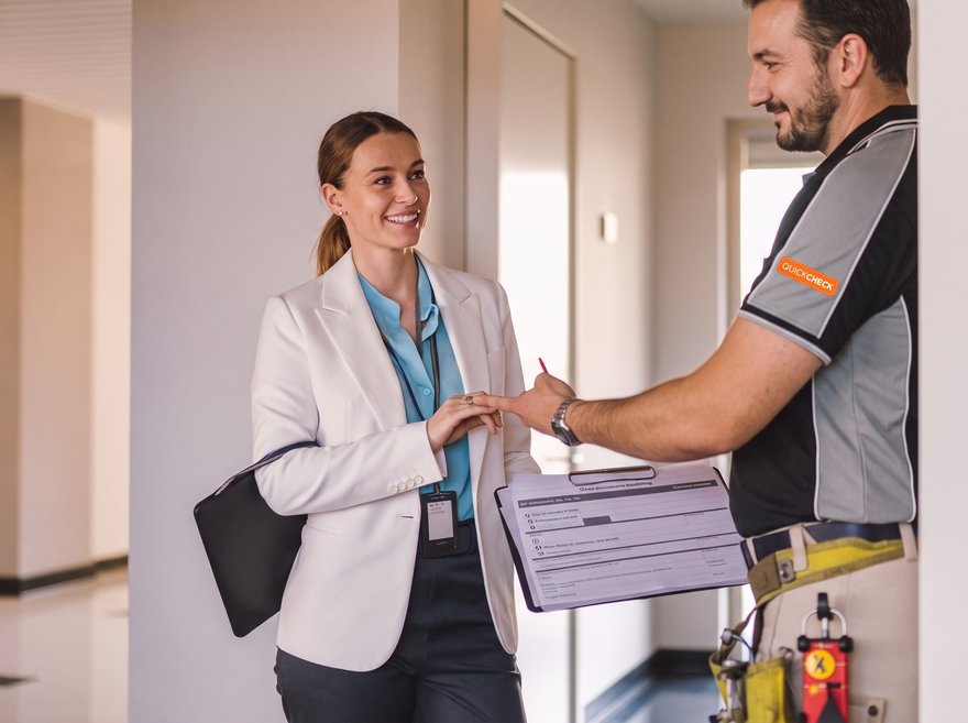 A property manager reviewing a smoke alarm compliance report with a Quickcheck electrician
